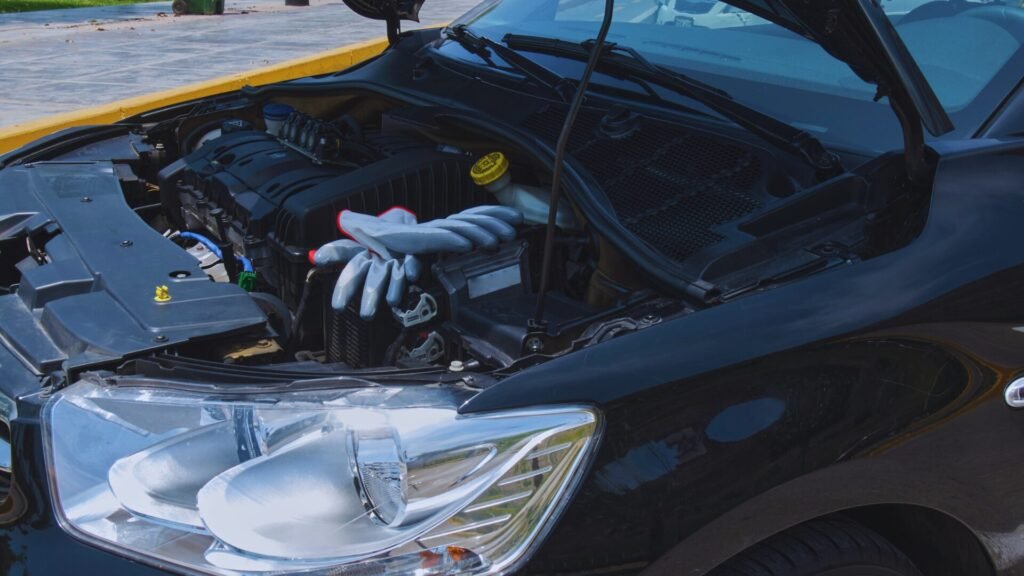 Detailed close-up of a black car engine bay with work gloves.