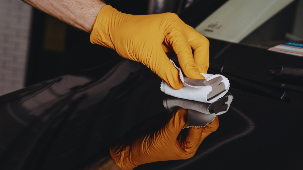 A detailer applies a ceramic coating on a black car in the Bronx.