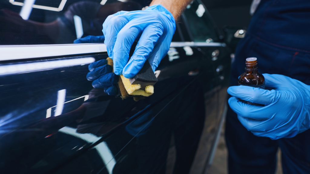 Hand applying ceramic coating product to a glossy black car.
